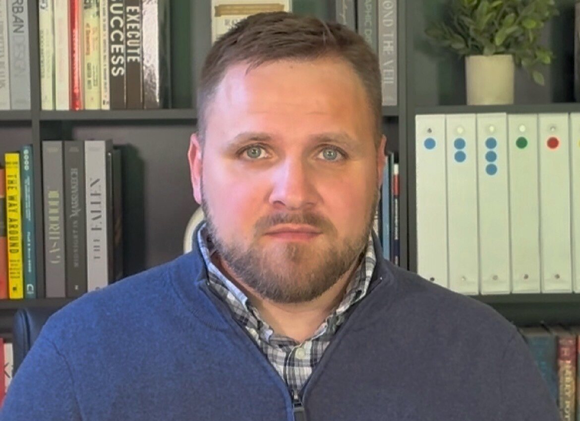 Josh Grubb seated in front of a bookshelf